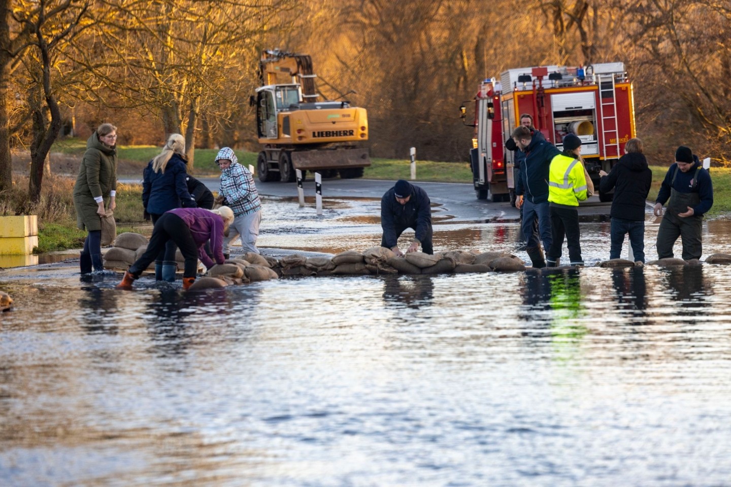 Helfer bauen mit Sandsäcken einen Deich auf einer Straße im thüringischen Windehausen.